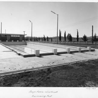 A black and white photograph of a half-empty swimming pool at Westbrook Training Centre. On the photograph is written: Works Department, July  ninetheen sixtyfive, Boys Home Westbrook, Swimming Pool.